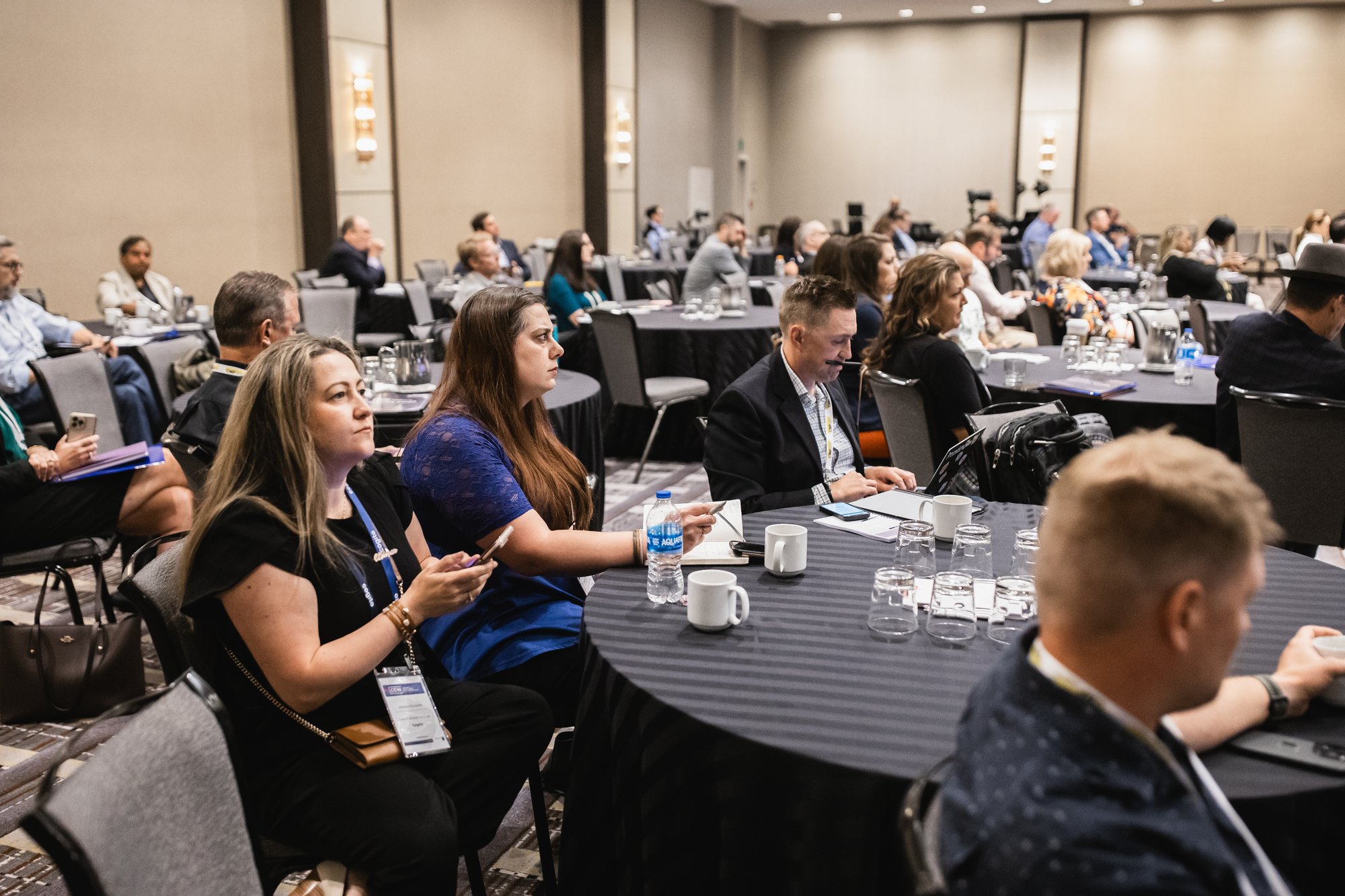 Group of attendees sitting in roundtables at a conference. 
